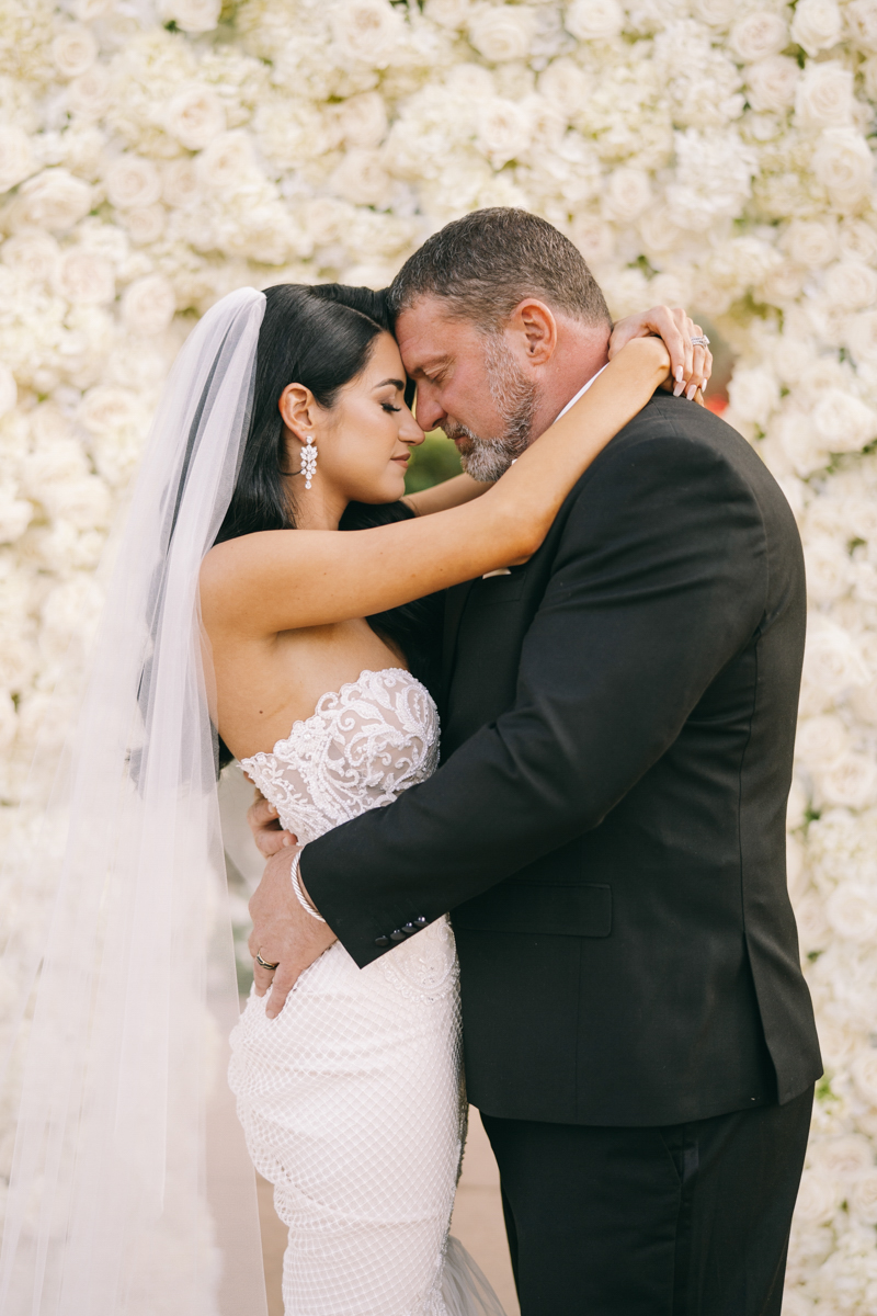 bride and groom portrait in front of white rose wall