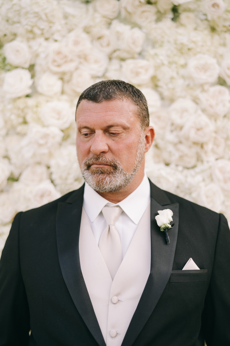 groom photo in front of rose wall