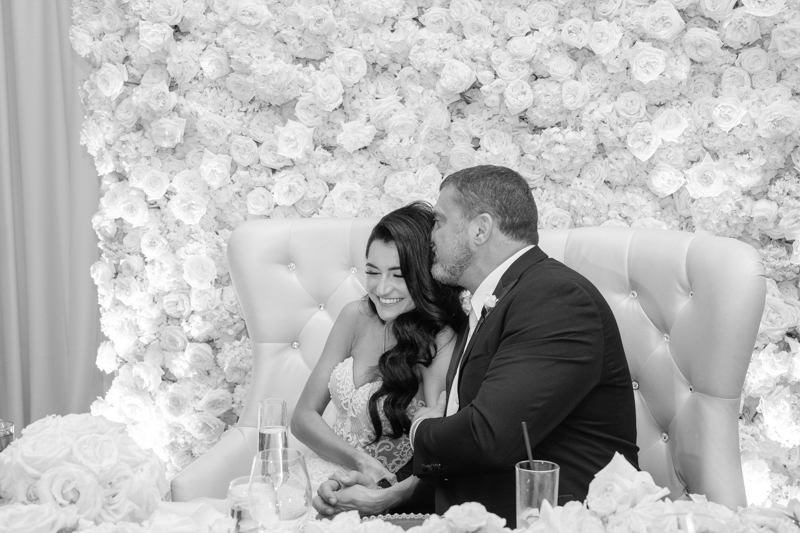 couple sitting in front of flower wall