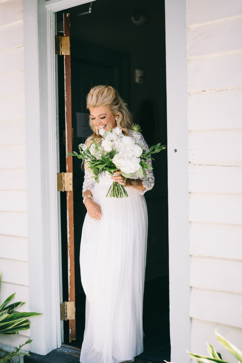 Smiling bride coming outside with flowers