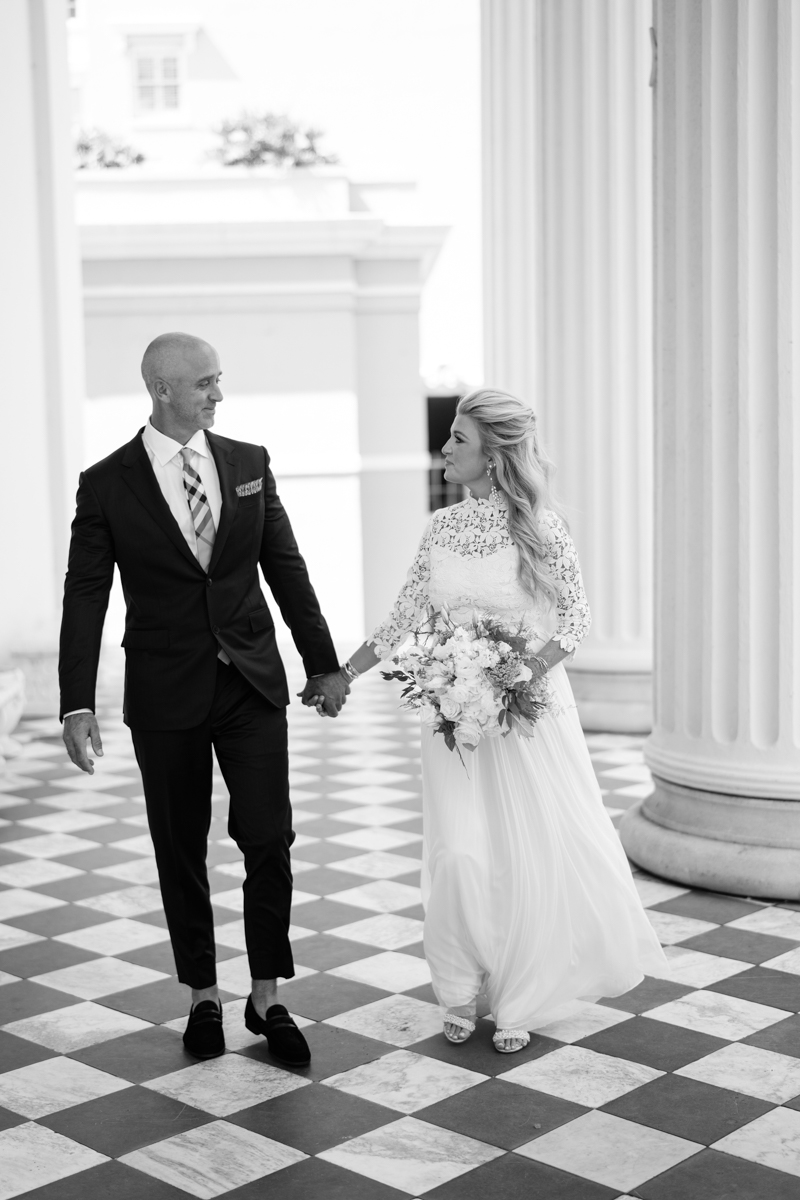 Black and white photo of charleston Luxury Bride and Groom walking together holding hands