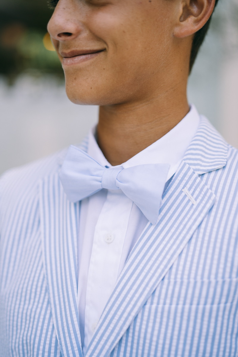 Young man wearing light blue and striped suit with blue bowtie
