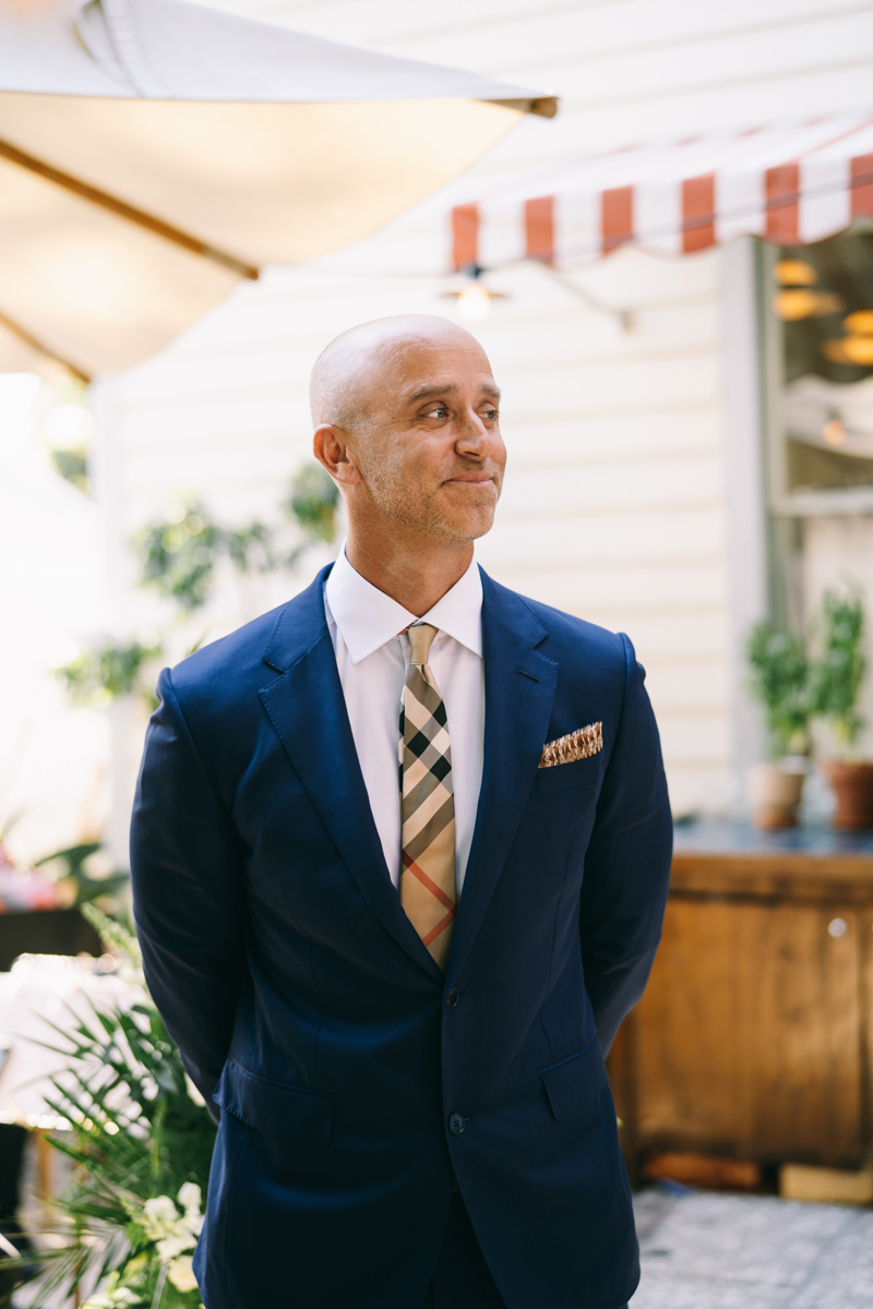 Groom waiting outside downtown Charleston hotel for his bride looking excited