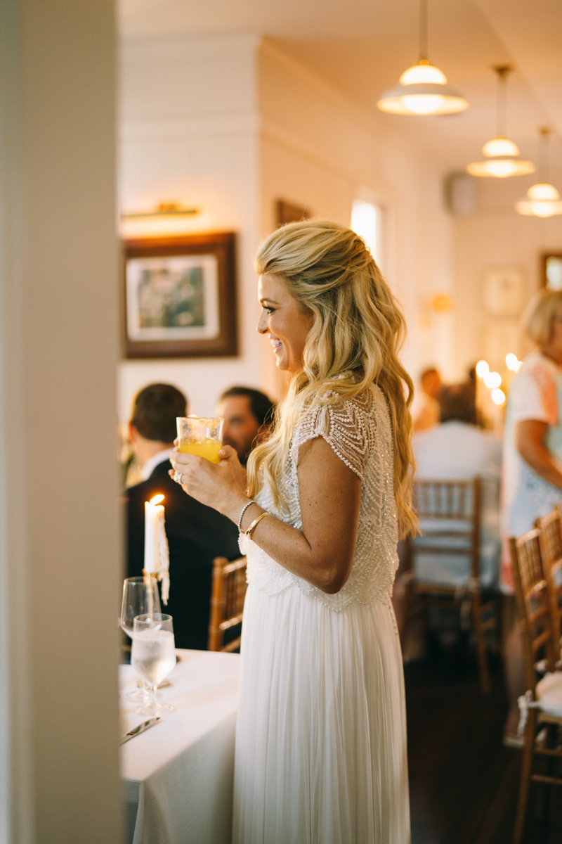 Bride smiling holding glass looking at guests