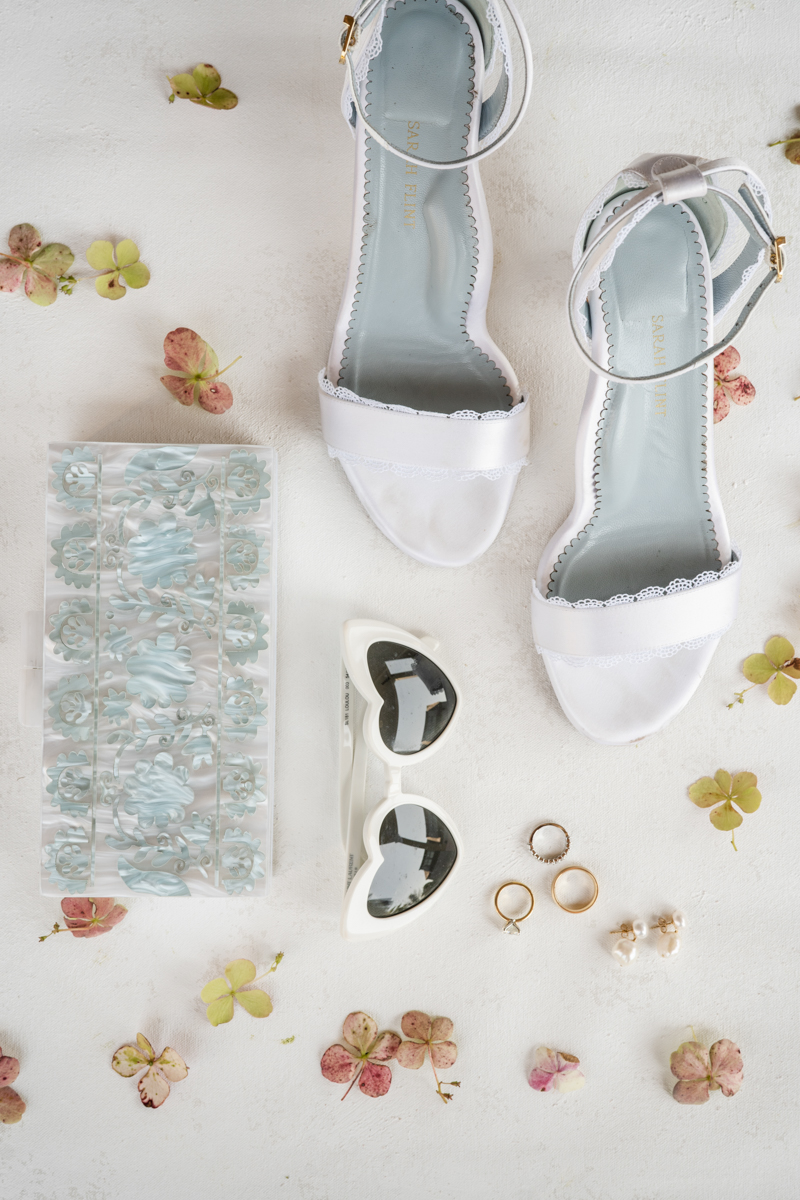White shoes and sunglasses with wedding rings as wedding details