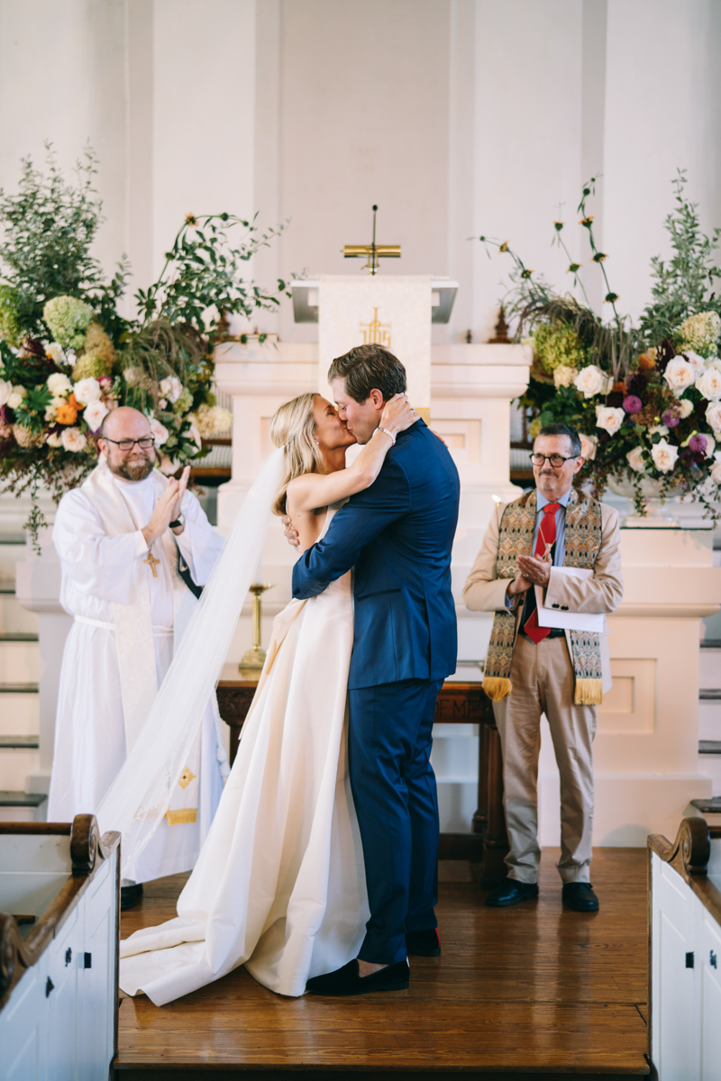 groom and bride kiss at altar