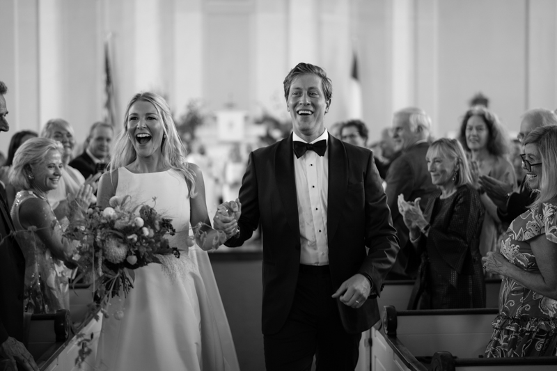 black and white photo bride and groom walking back down the aisle together
