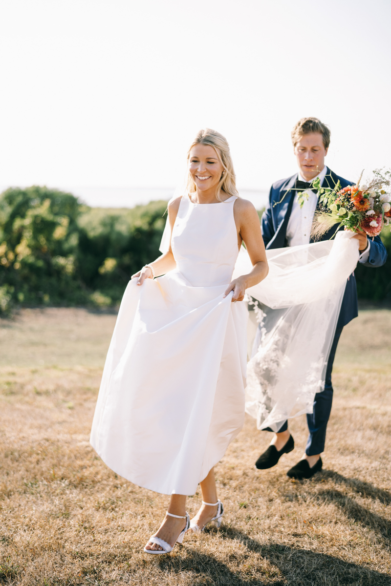 groom is holding bride's dress and flowers
