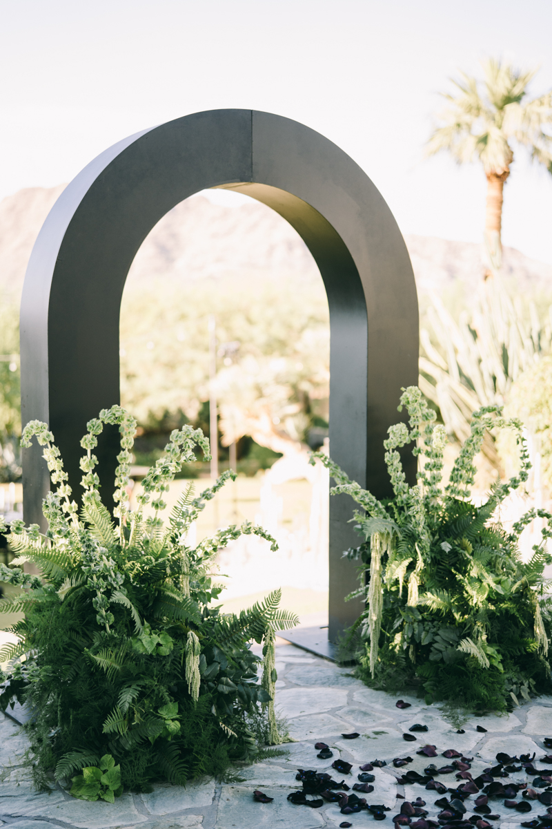 black wedding arch with greenery