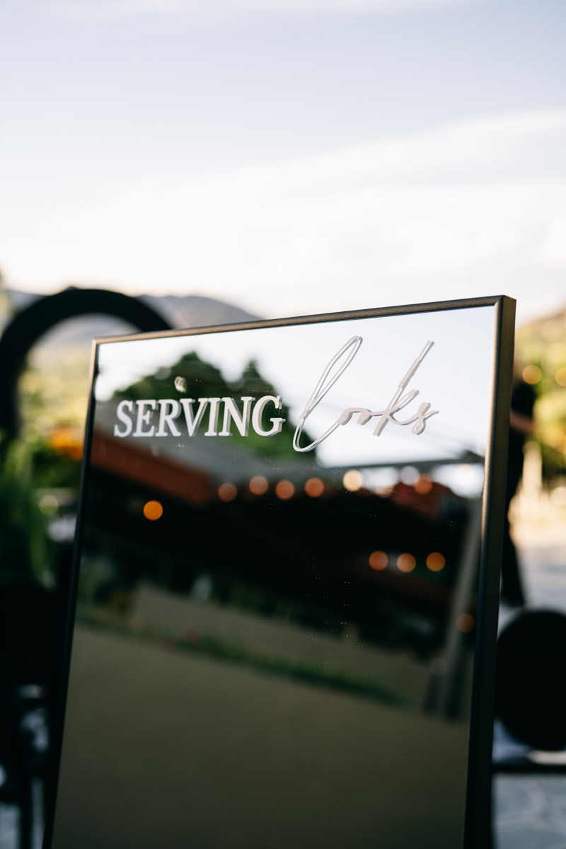wedding decorations of a mirror that says 'serving looks' in outdoor reception