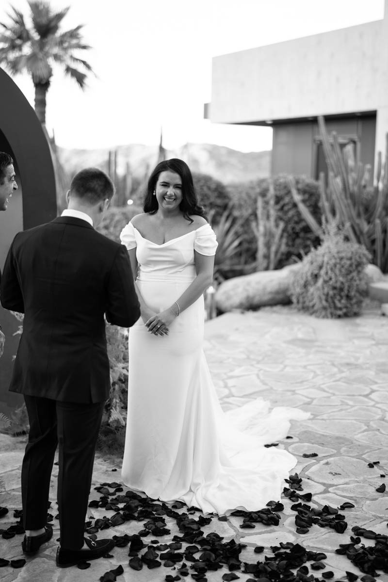 Black and white photo of bride smiling at the groom during the wedding ceremony