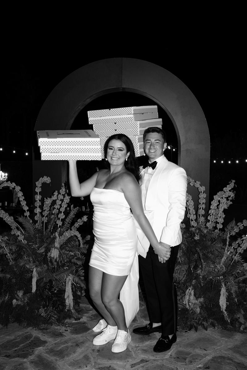 black and white photo of bride and groom holding pizza boxes