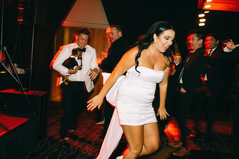 bride and groom on the dance floor with the groom holding a dog 