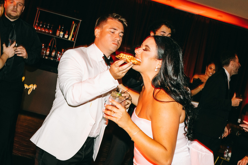 groom feeding pizza to bride at their reception