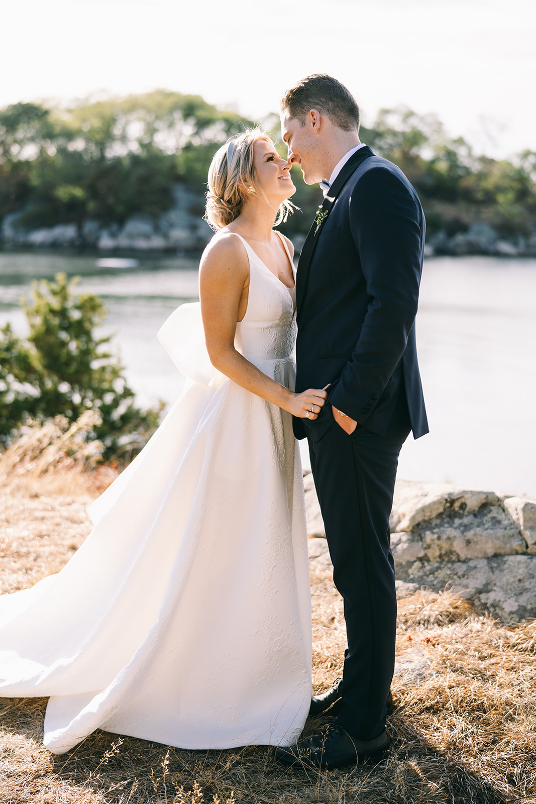 Groom looking at bride who is looking up at him with the bay in the background