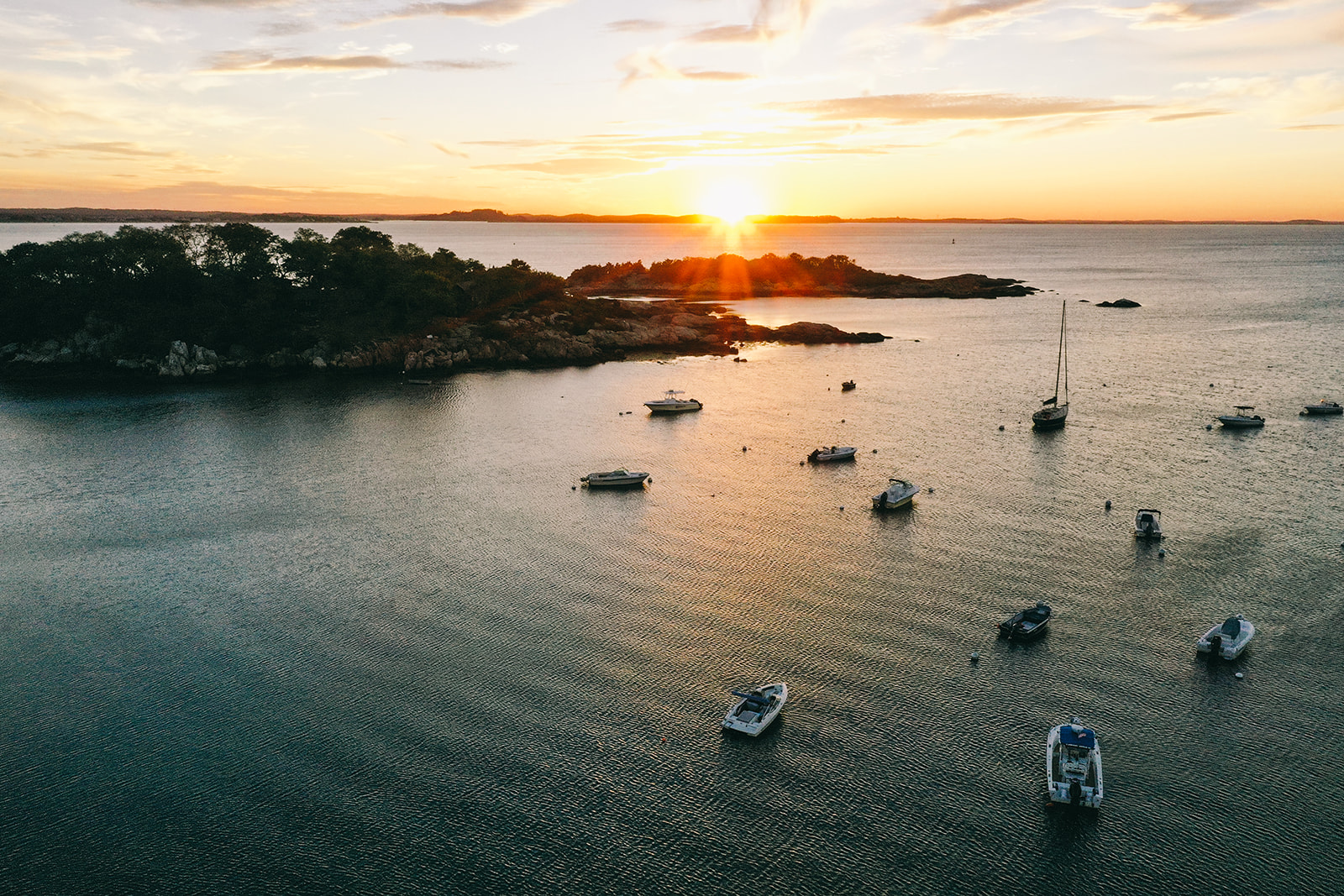 Sunset over the bay in Gloucester, Massachusetts with boats in the water and small islands with trees