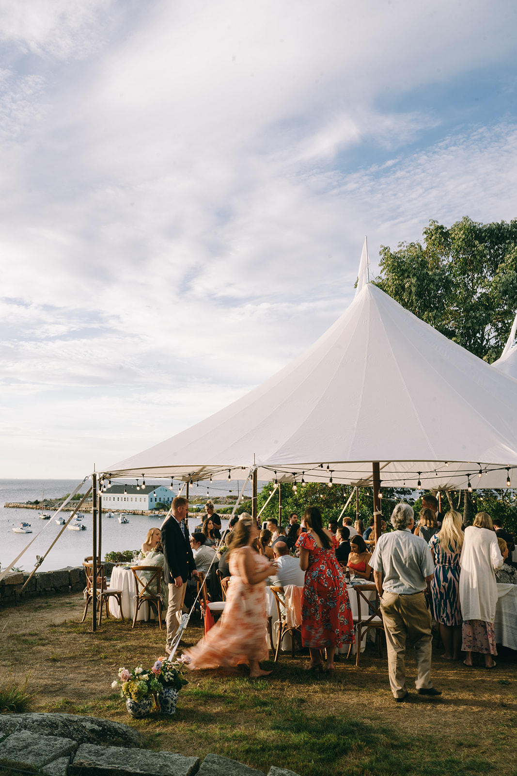Wedding guests underneath event tents on the bay in colorful clothing