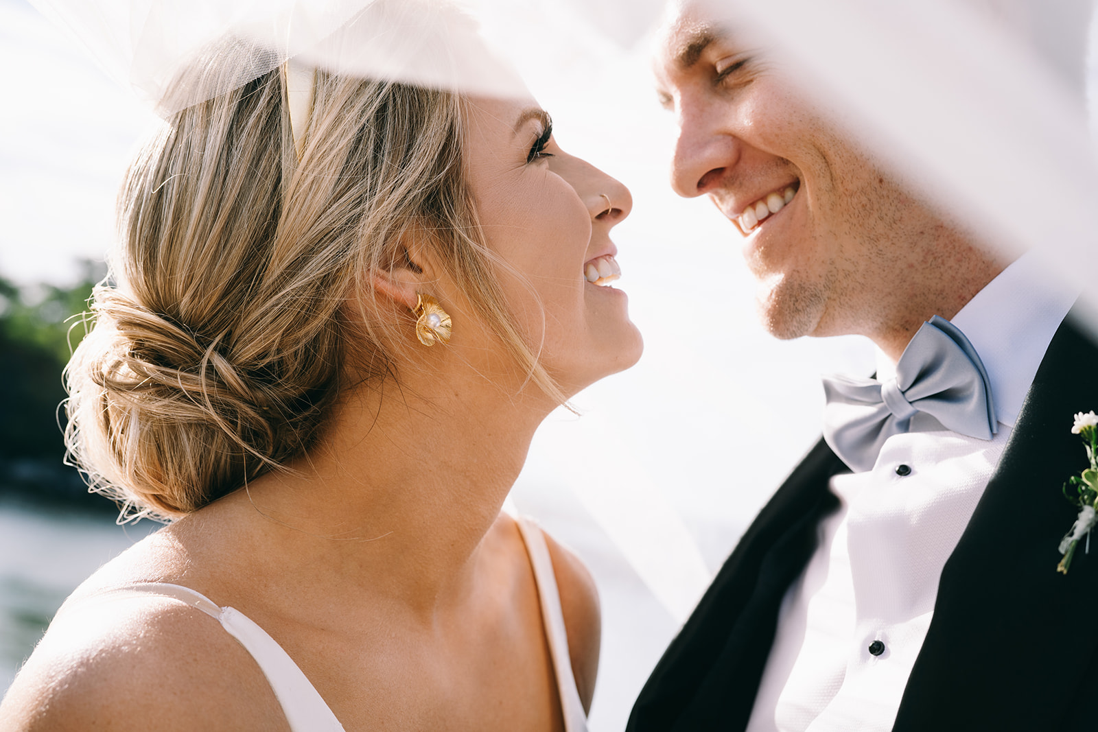 Close up of bride and groom looking at each other and smiling underneath the bride's veil