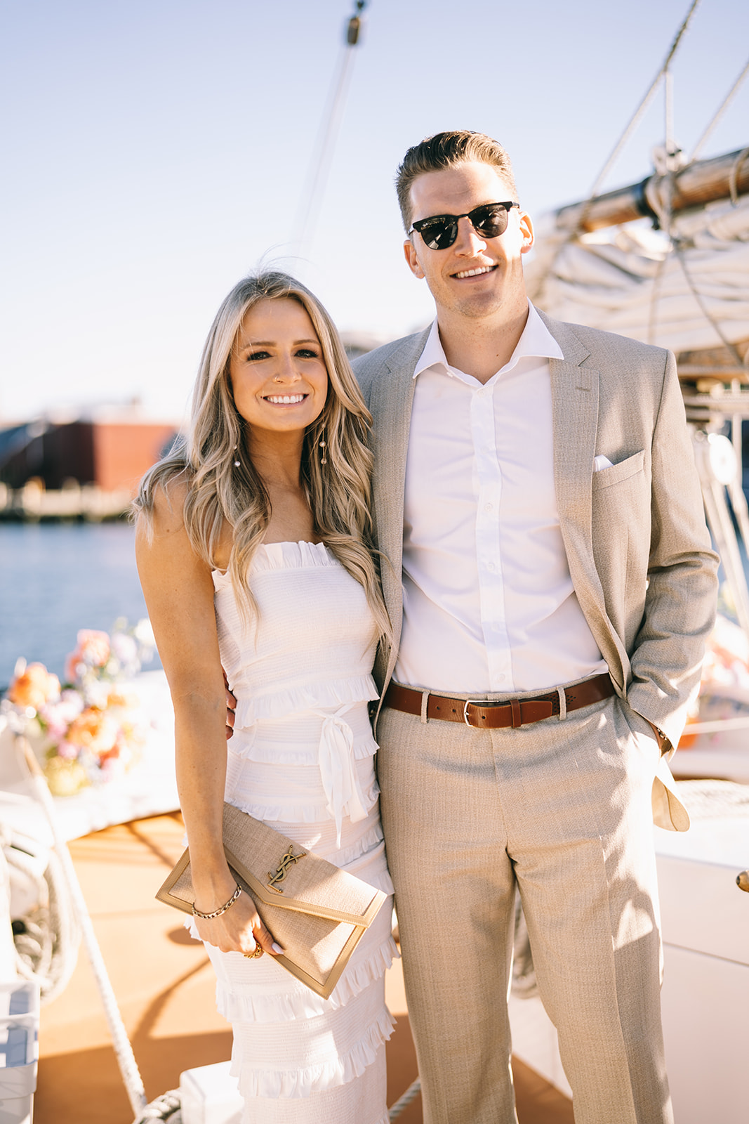 welcome dinner sail Couple standing close to each other on a sailboat with clear skies and woman holding a beige purse