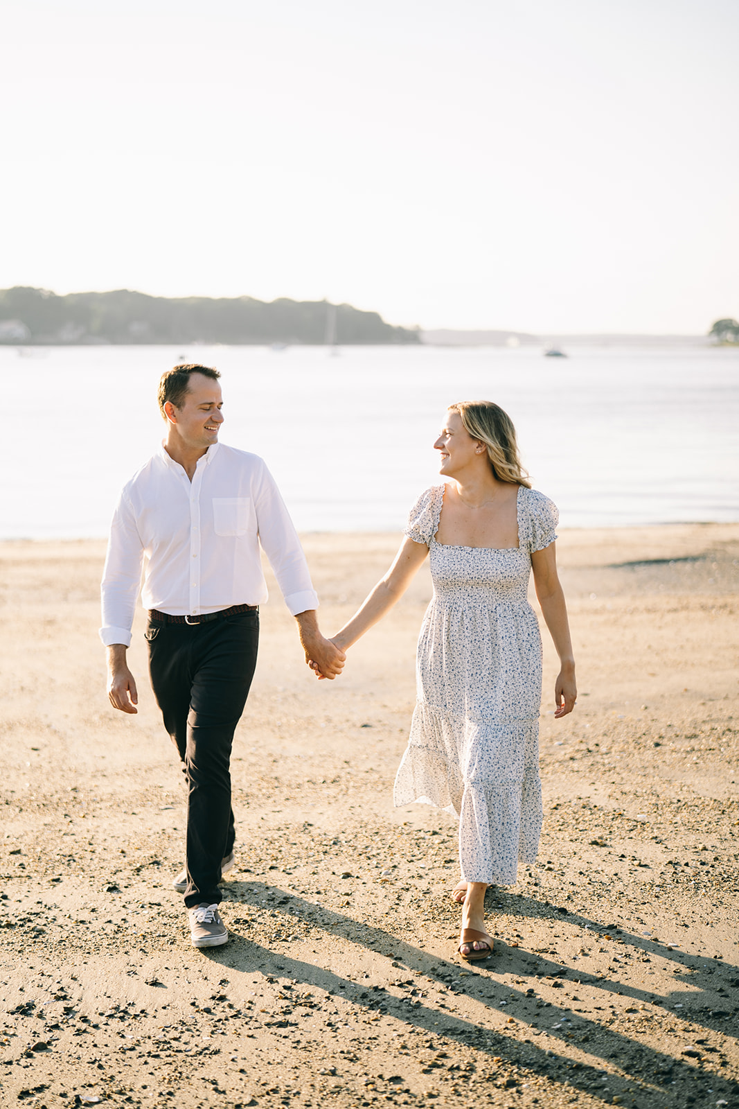 Woman in dress walking along the sandy beach with man in white shirt and slacks 