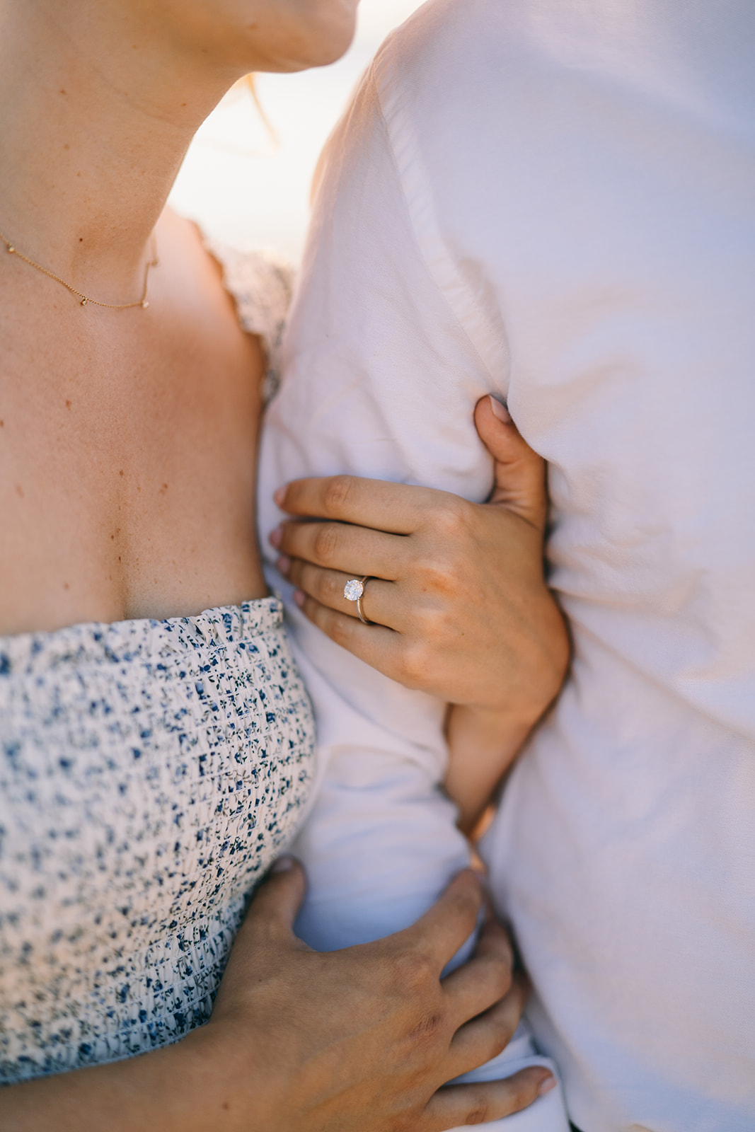 Close up of woman holding onto a man's arm showing off her engagement ring 