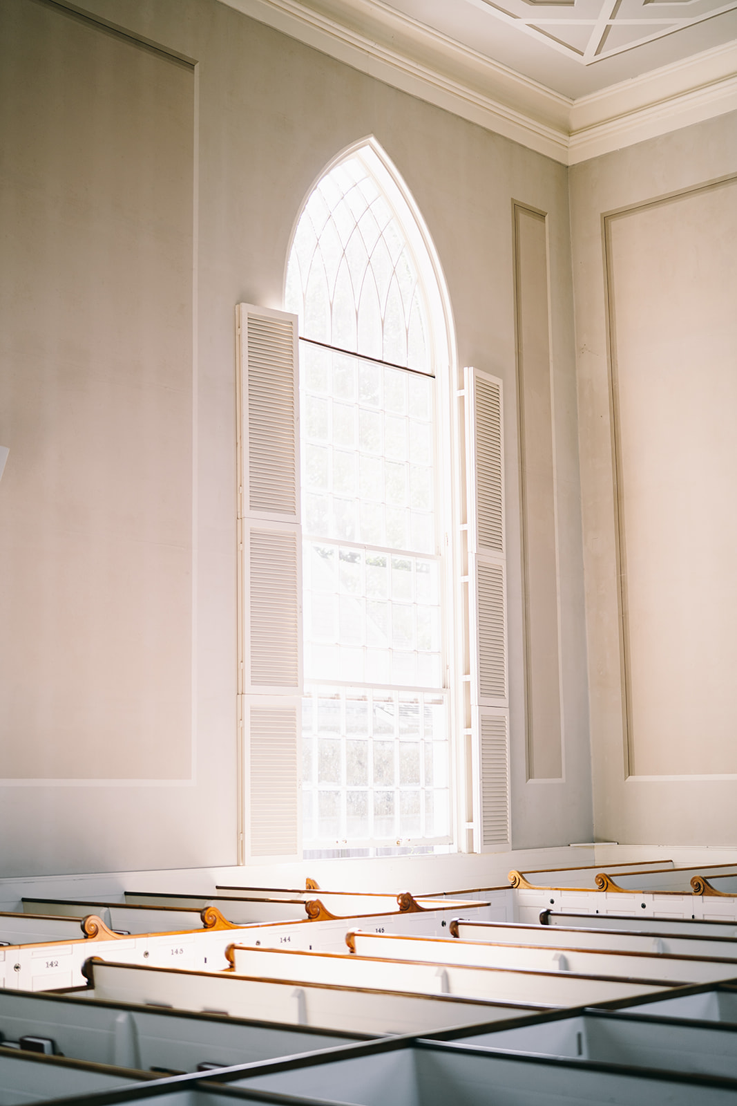 Empty church with white pews and white walls and one giant window 