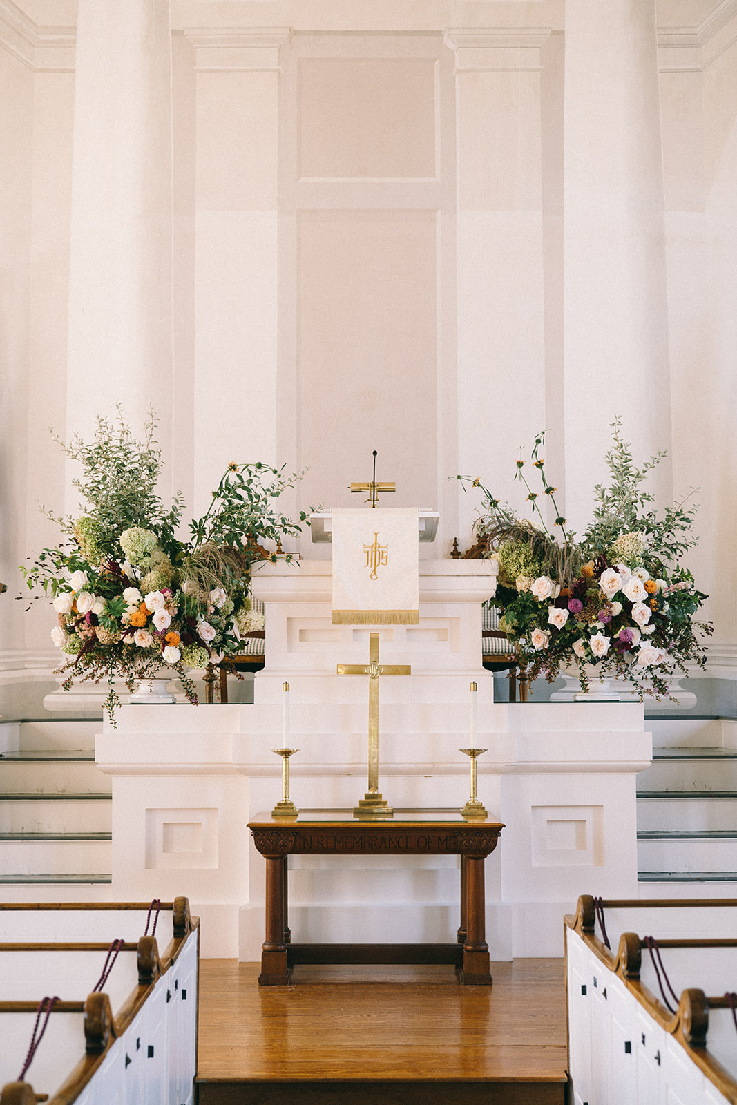 Altar with cross and flowers and flower arrangements on either side 