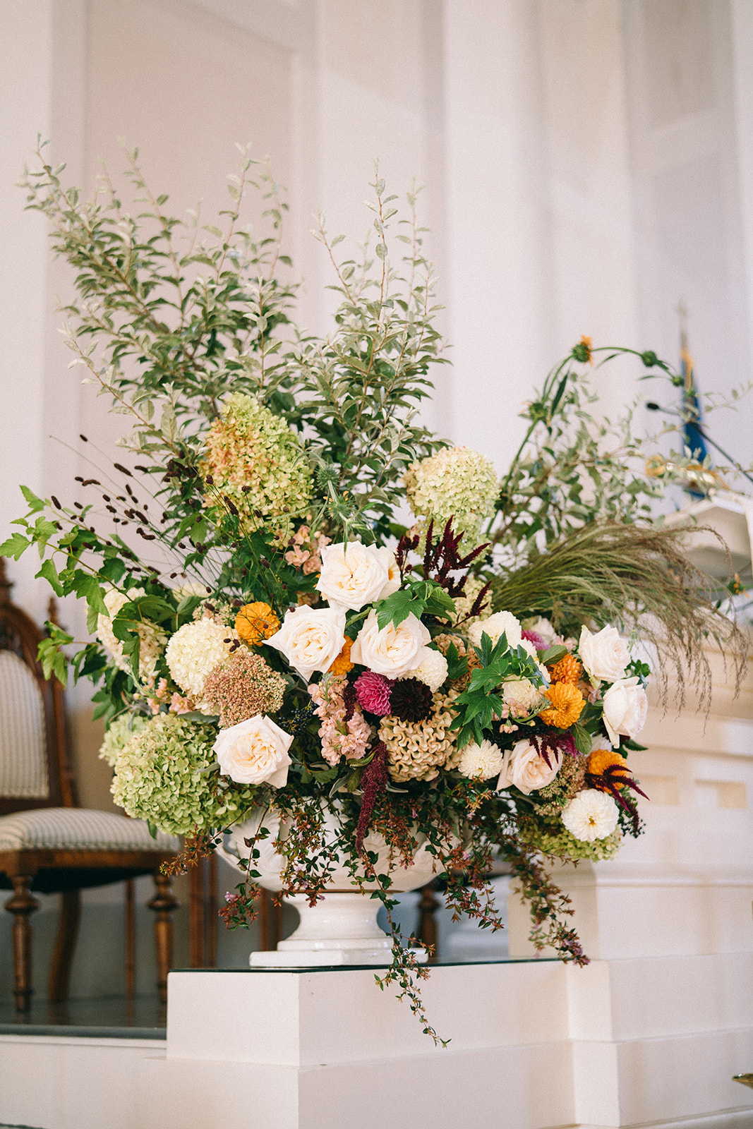 FLower arrangement in church with hydrangeas, dahlias, and greenery