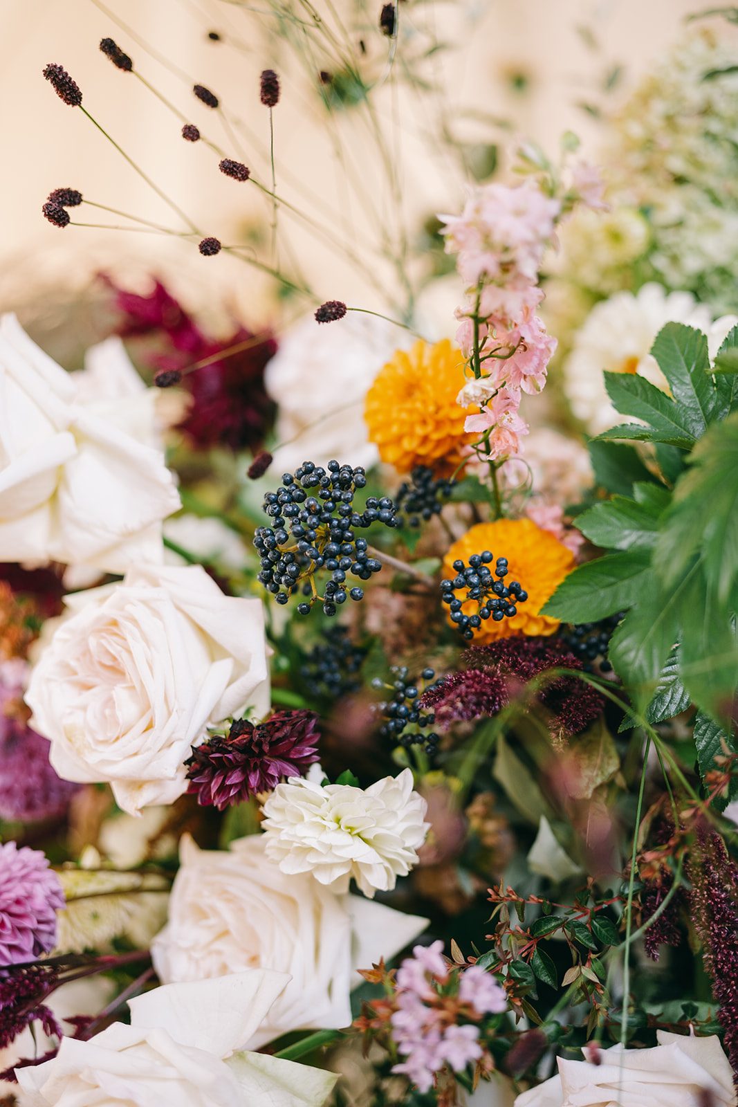 Close up flower arrangement with roses, dahlias, orange flowers and berries