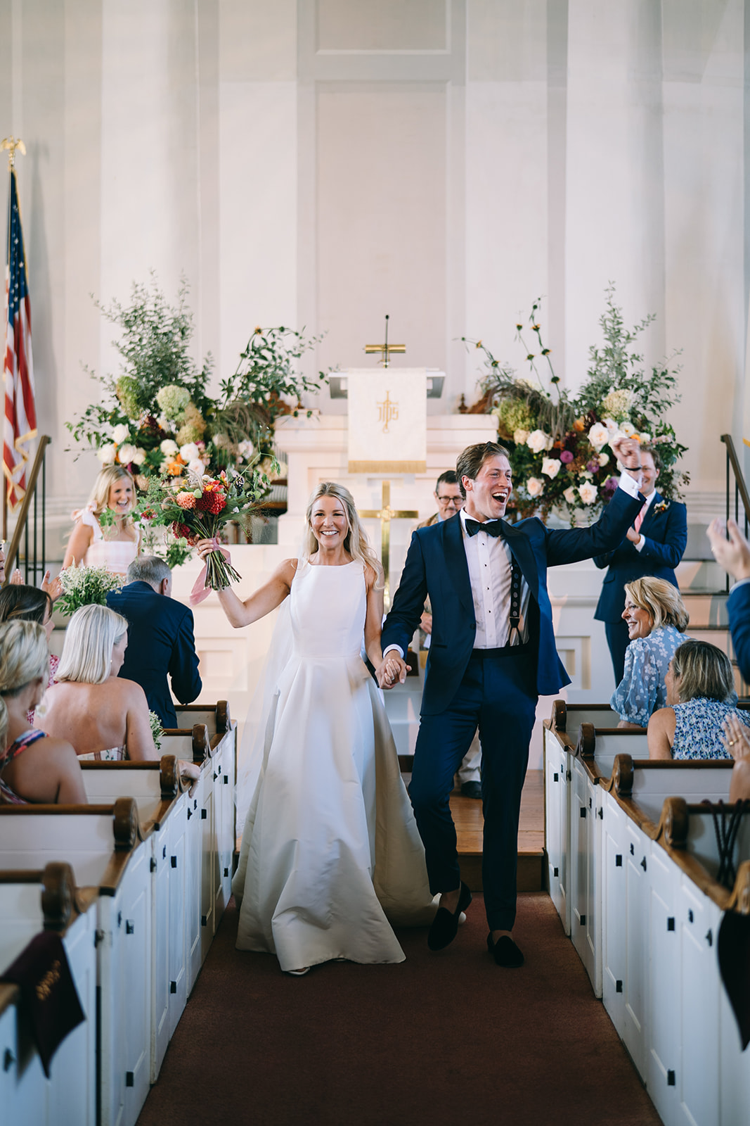 Bride and groom walking down the aisle after being marries smiling at their guests