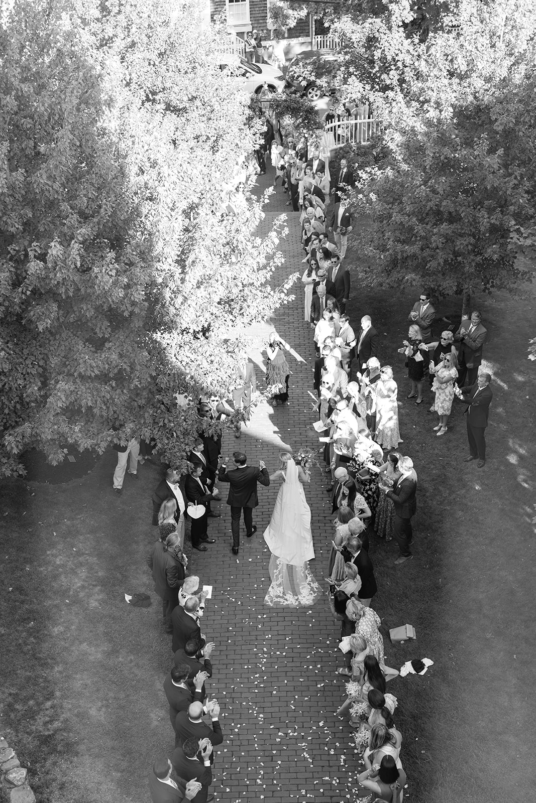 Aerial shot of bride and groom leaving church in black and white 