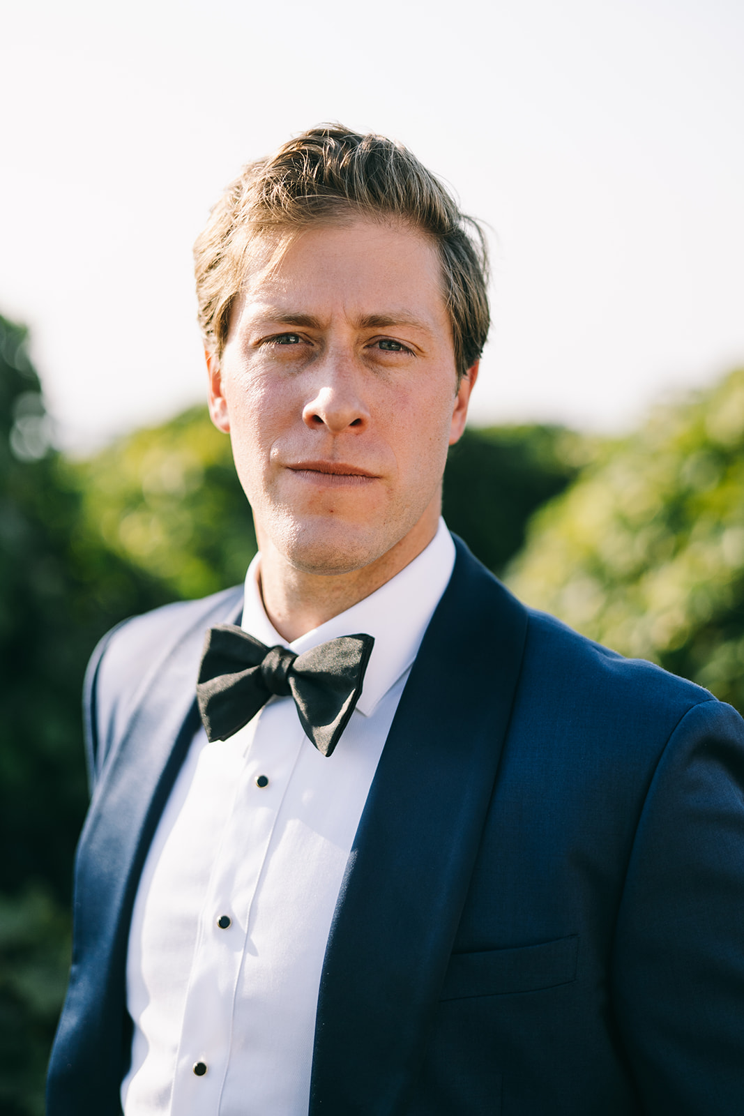 Close up of groom in blue suit looking into camera seriously