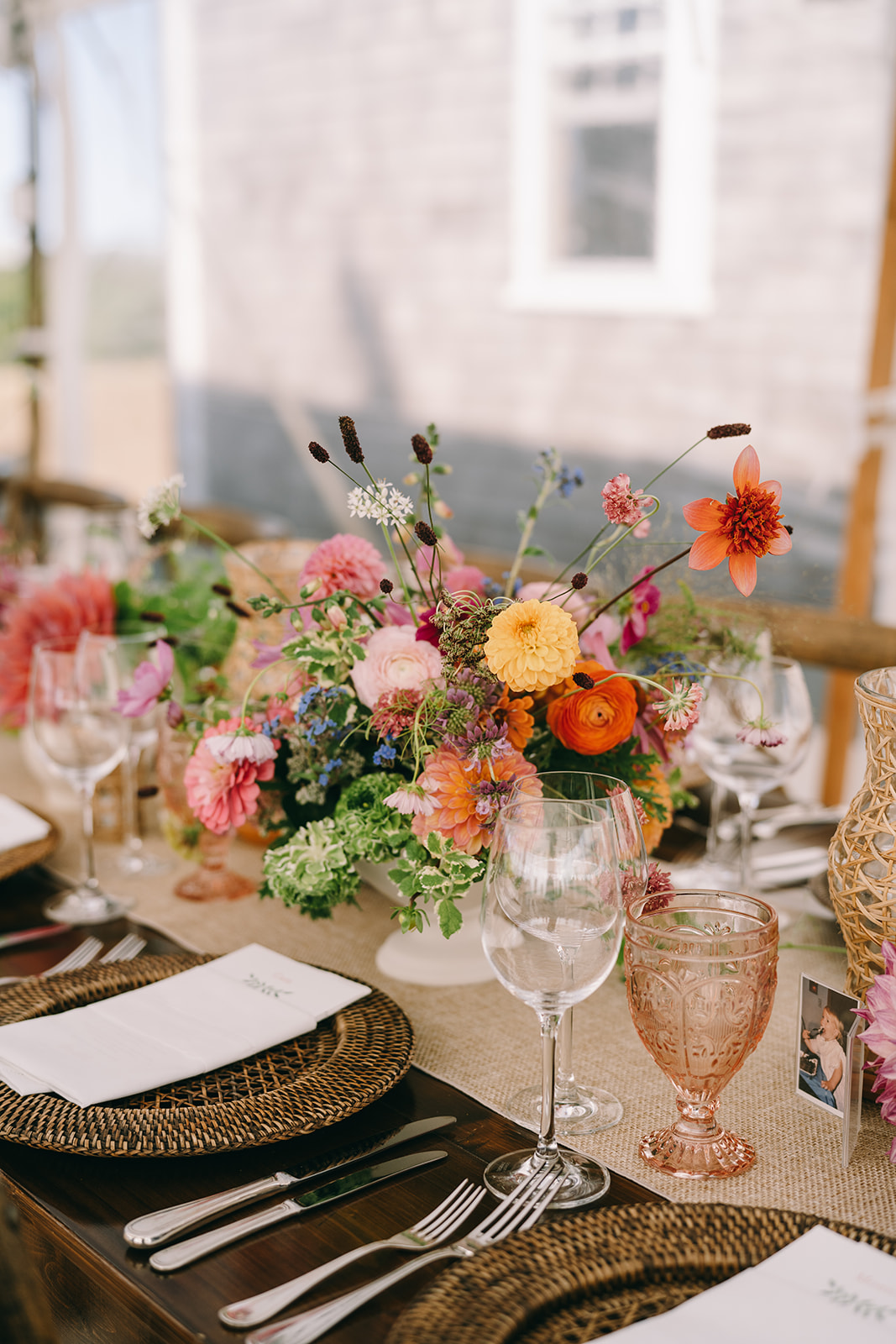 Table setting with colorful flowers and burlap table runners and wicker plate holders and pink goblets