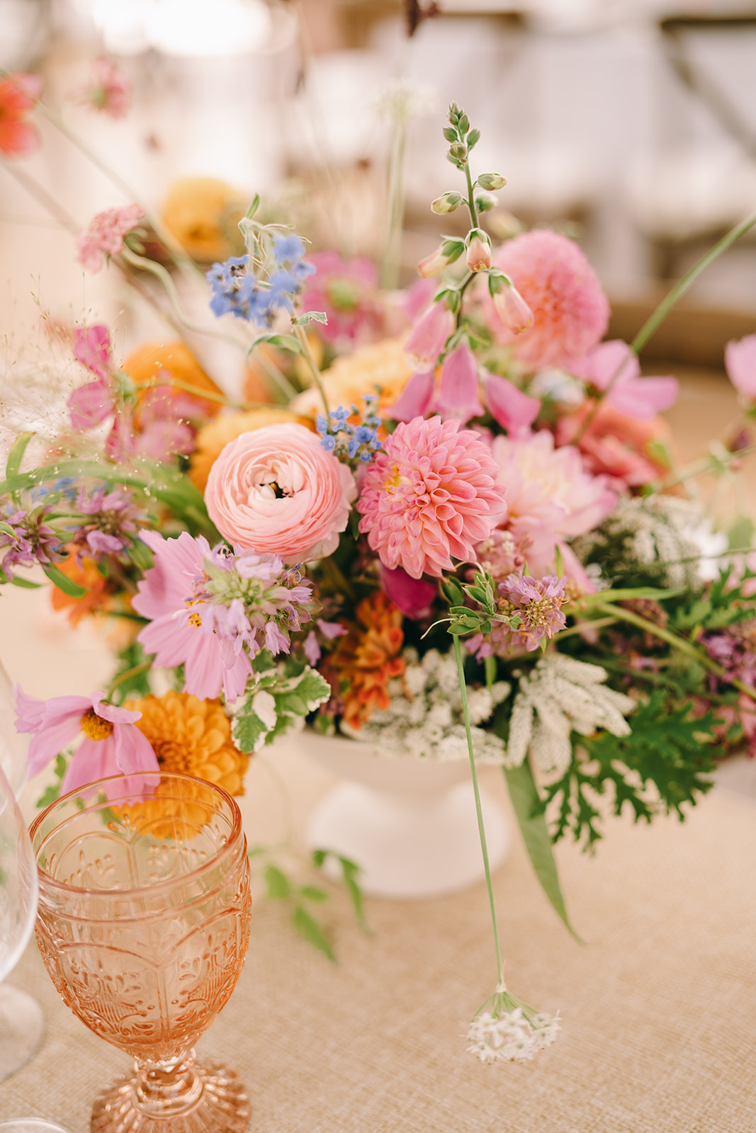 Flower arrangement with pink flowers next to a pink goblet at luxury wedding