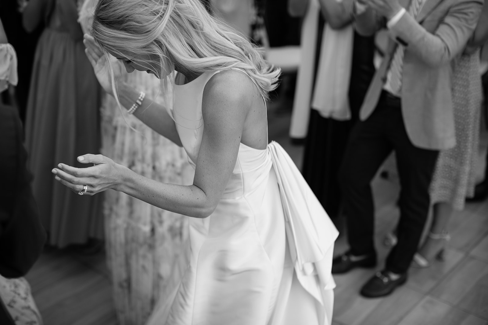 Candid moment of bride looking down and laughing about to clap her hands 