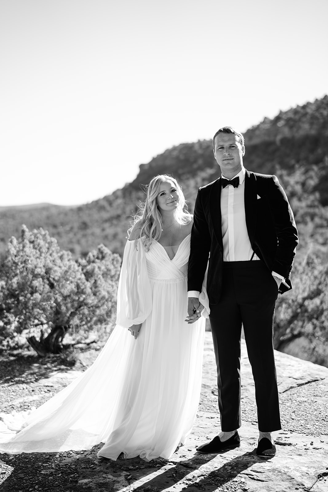 Close up of bride and groom holding hands and looking serious into camera