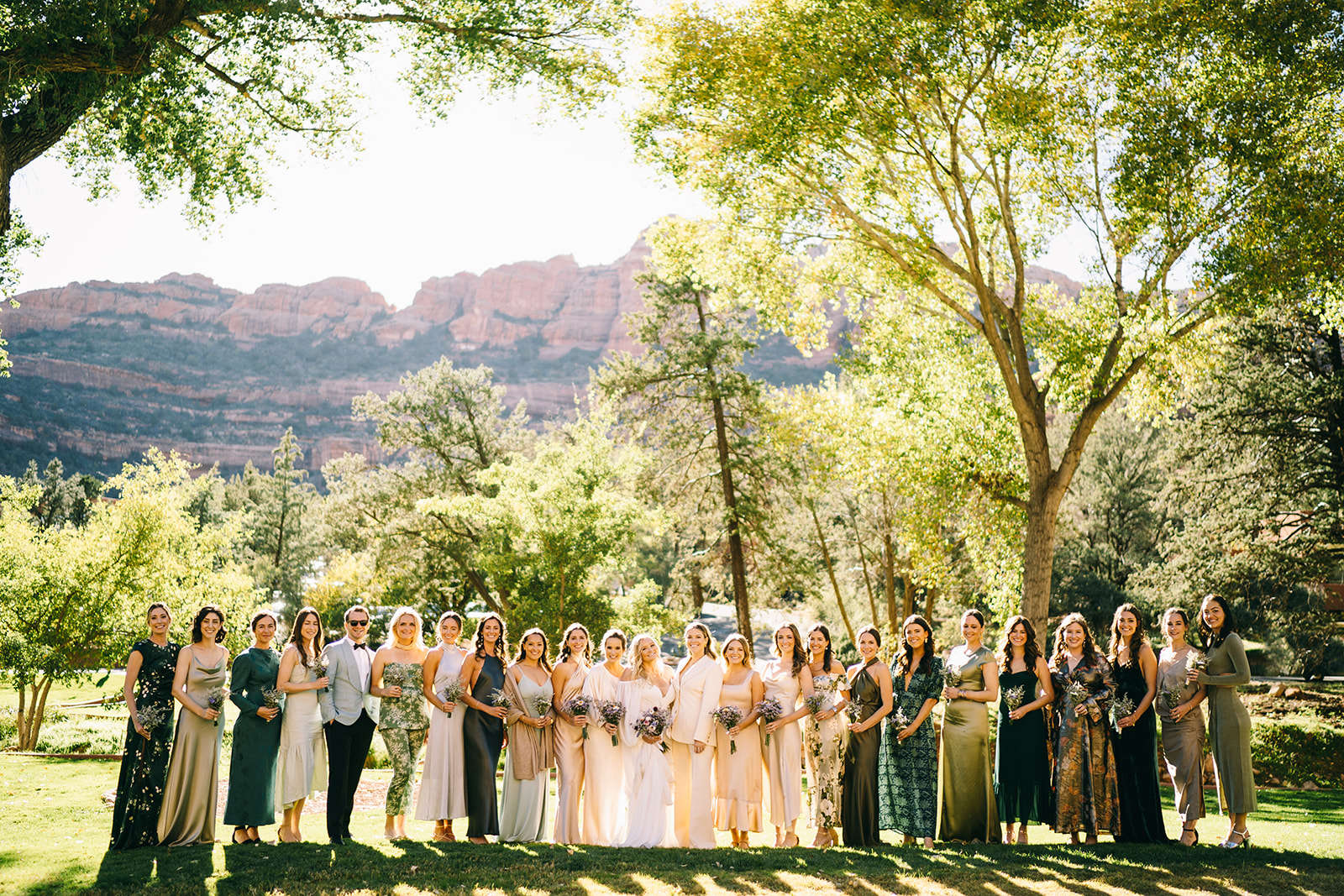 Bridal party in various shades of green with a back drop of trees and mountains in Sedona