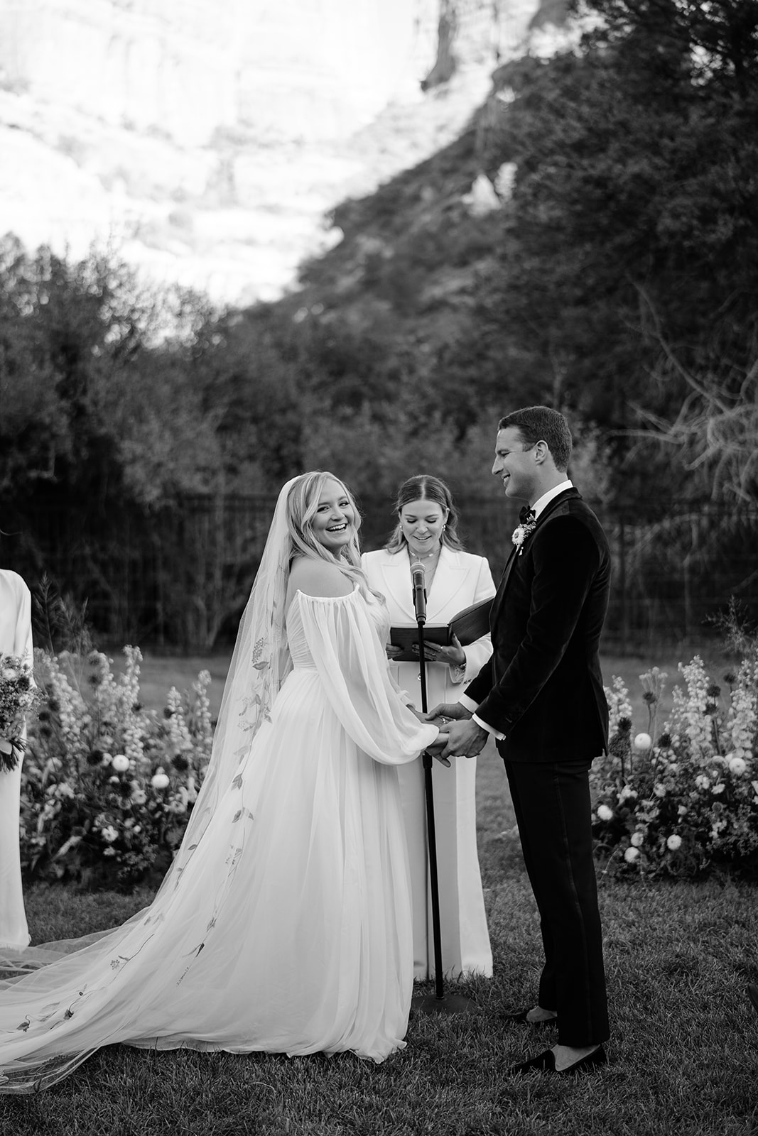 Bride and groom at the altar and the bride is looking at all of her guests and the groom is looking at her smiling 