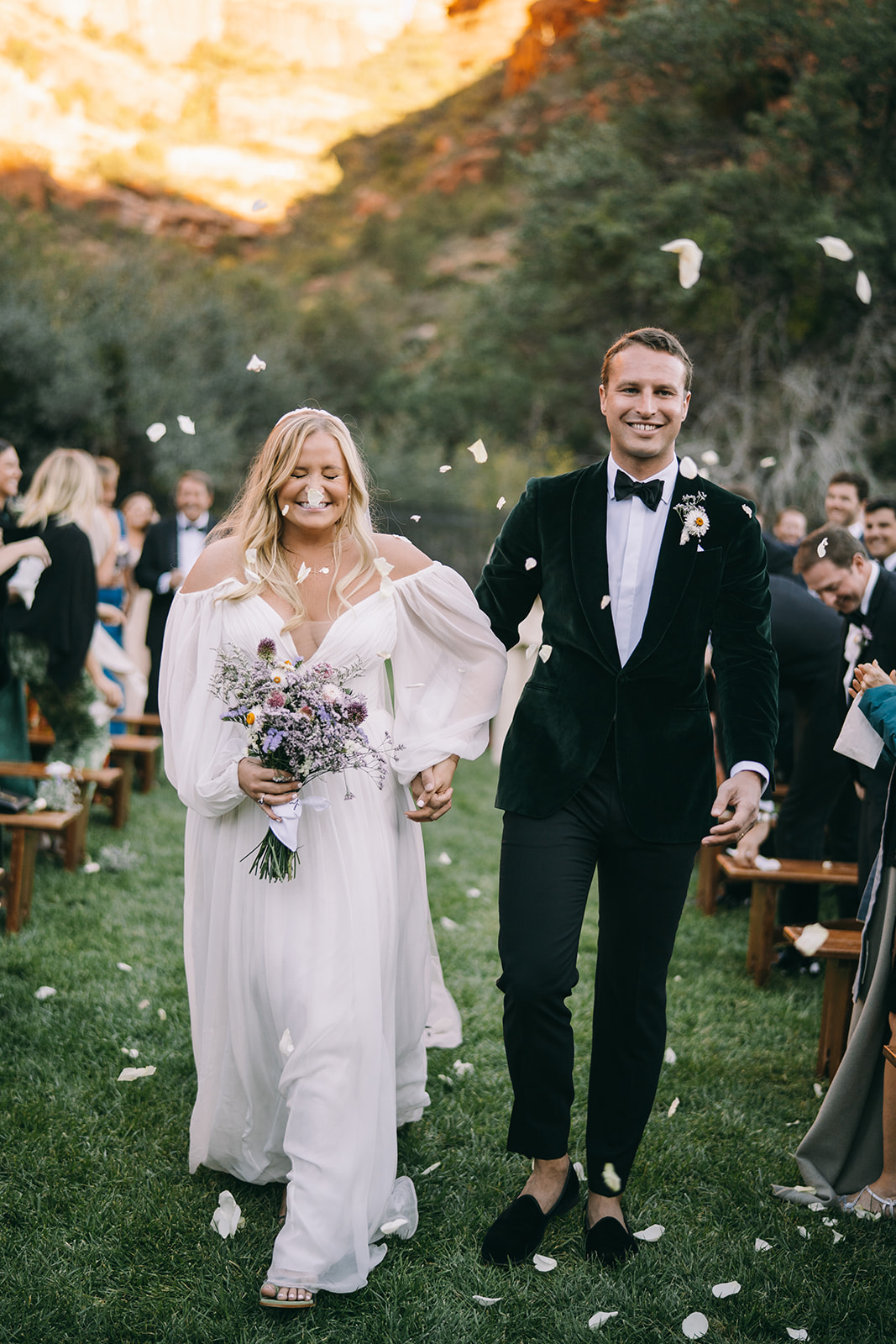 Sedona mountains in background of bride and groom walking down the aisle together smiling 