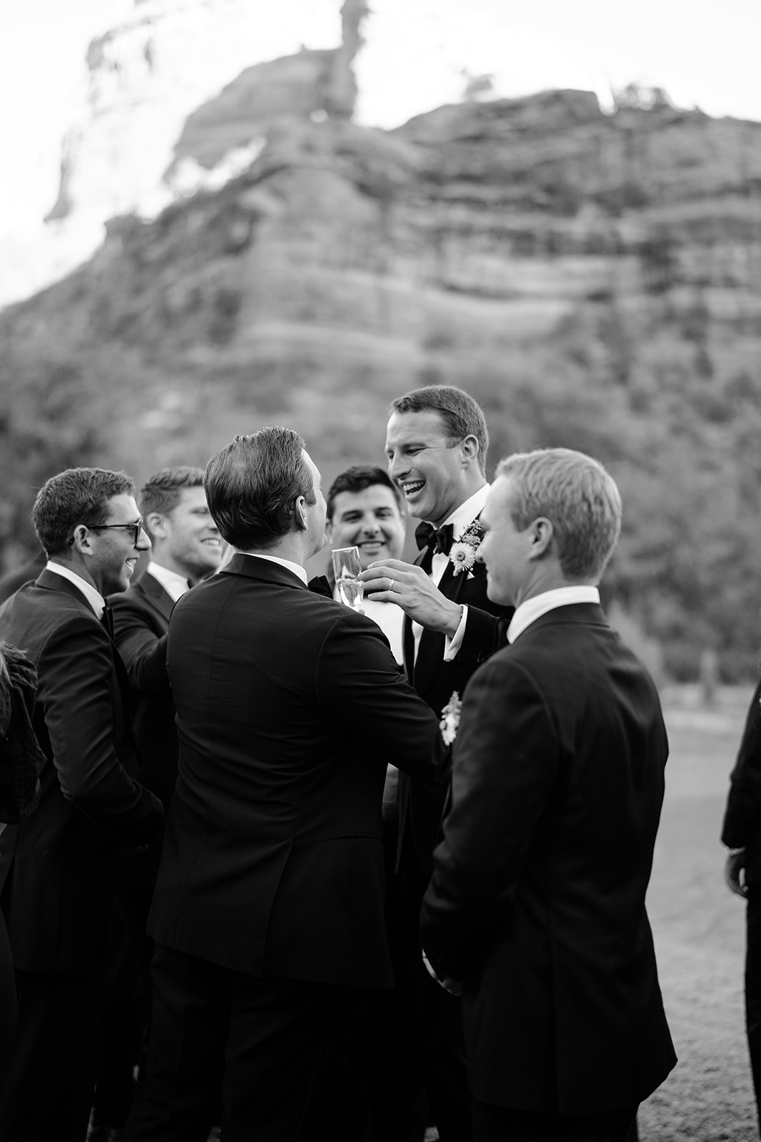 Groom with his groomsmen laughing and talking together in black and white 
