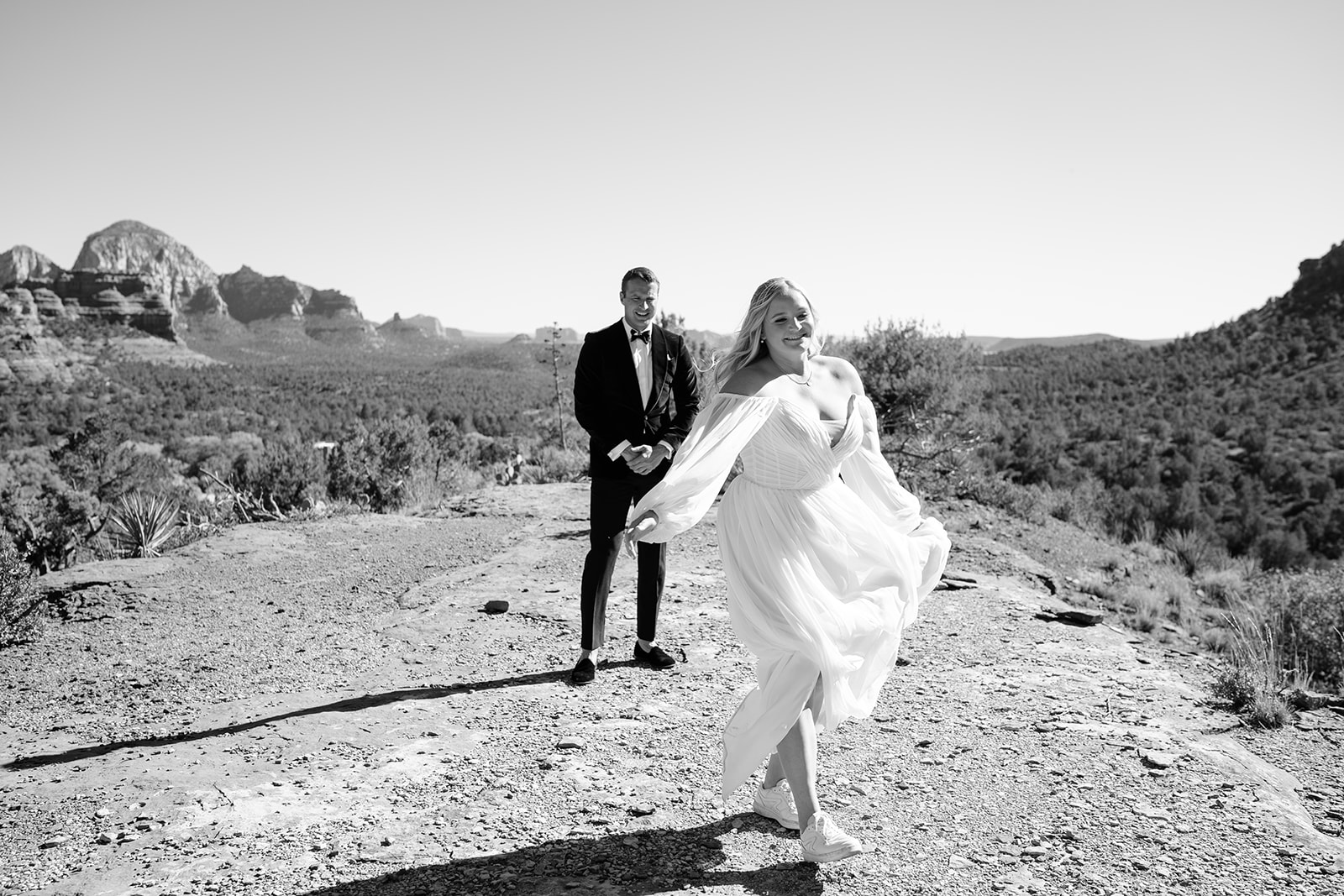 Bride twirling while groom watches her smiling