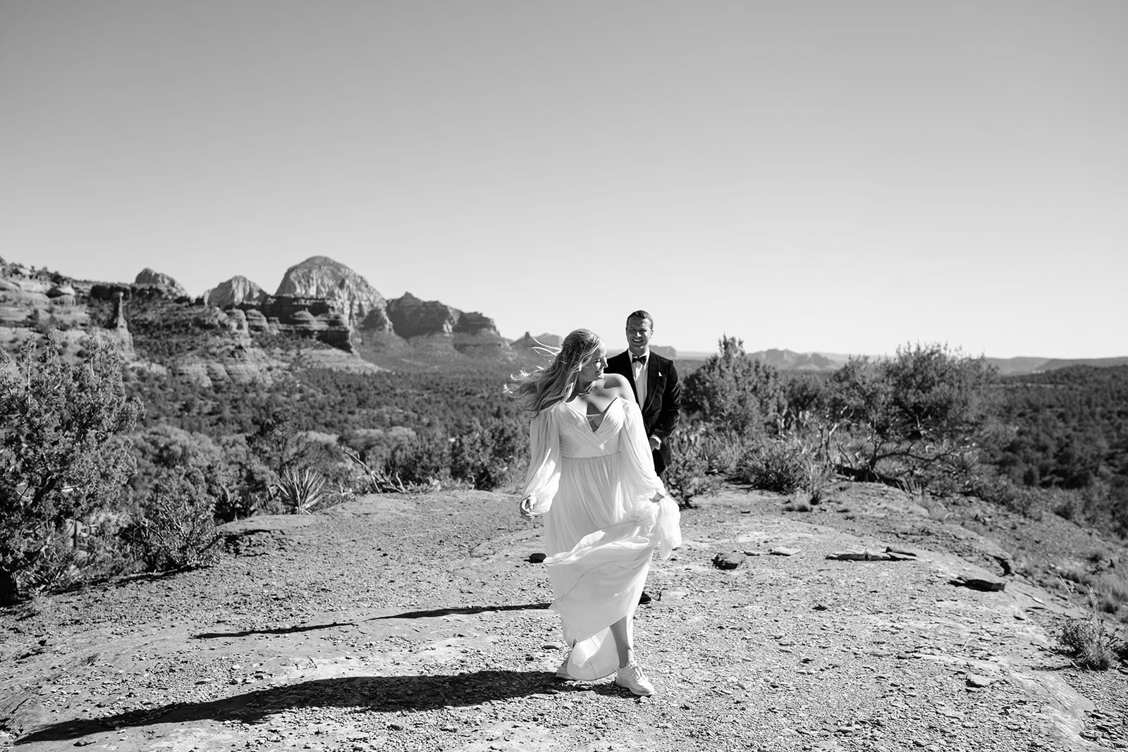 Groom is several feet behind bride and bride is looking back at him 