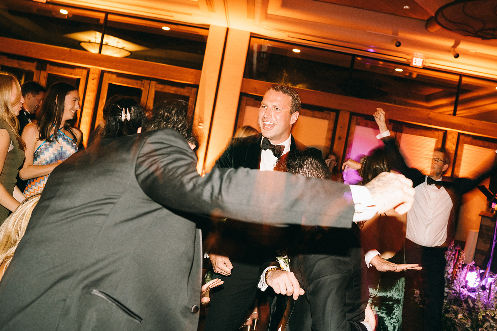 Groom and wedding guests dancing and laughing with their hands in the air