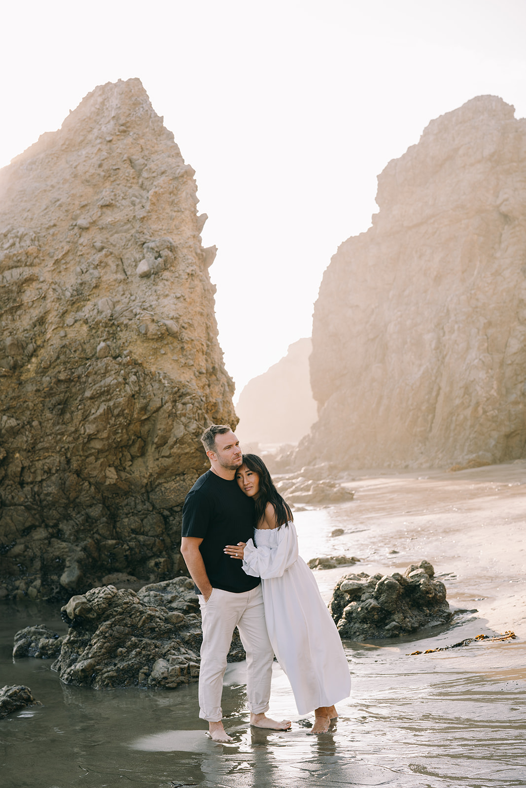 Couple posing for engagement photos along the coast of  malibu engagement el matador beach california
