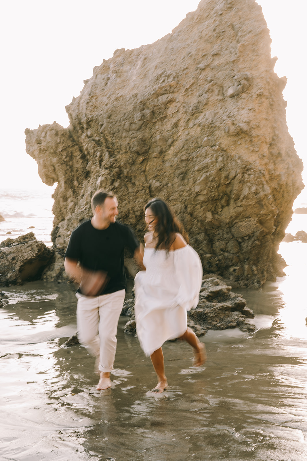 Slightly blurry photo of couple running and laughing malibu engagement el matador beach california