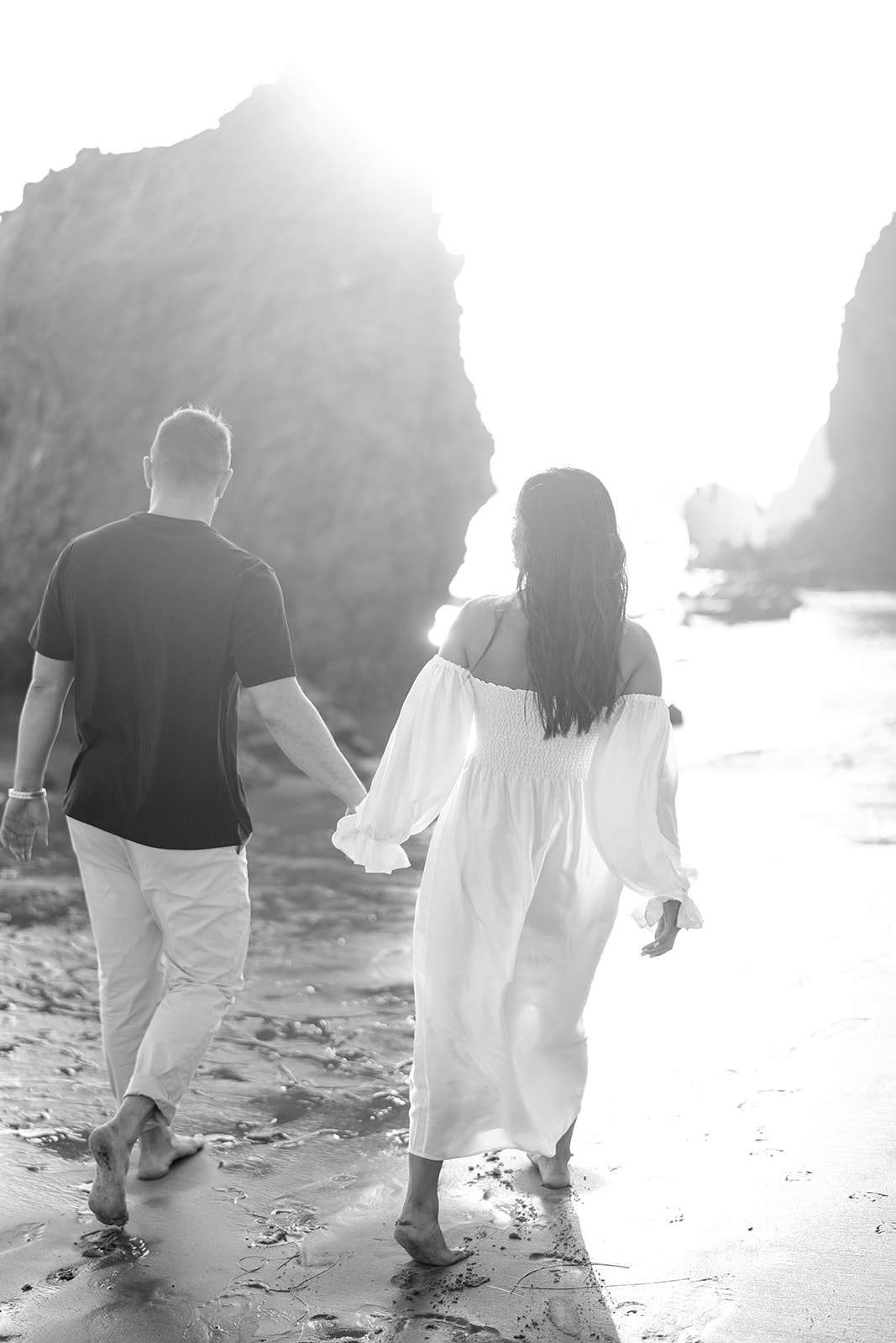 Sun shining on couple walking along the beach holding hands malibu engagement el matador beach california