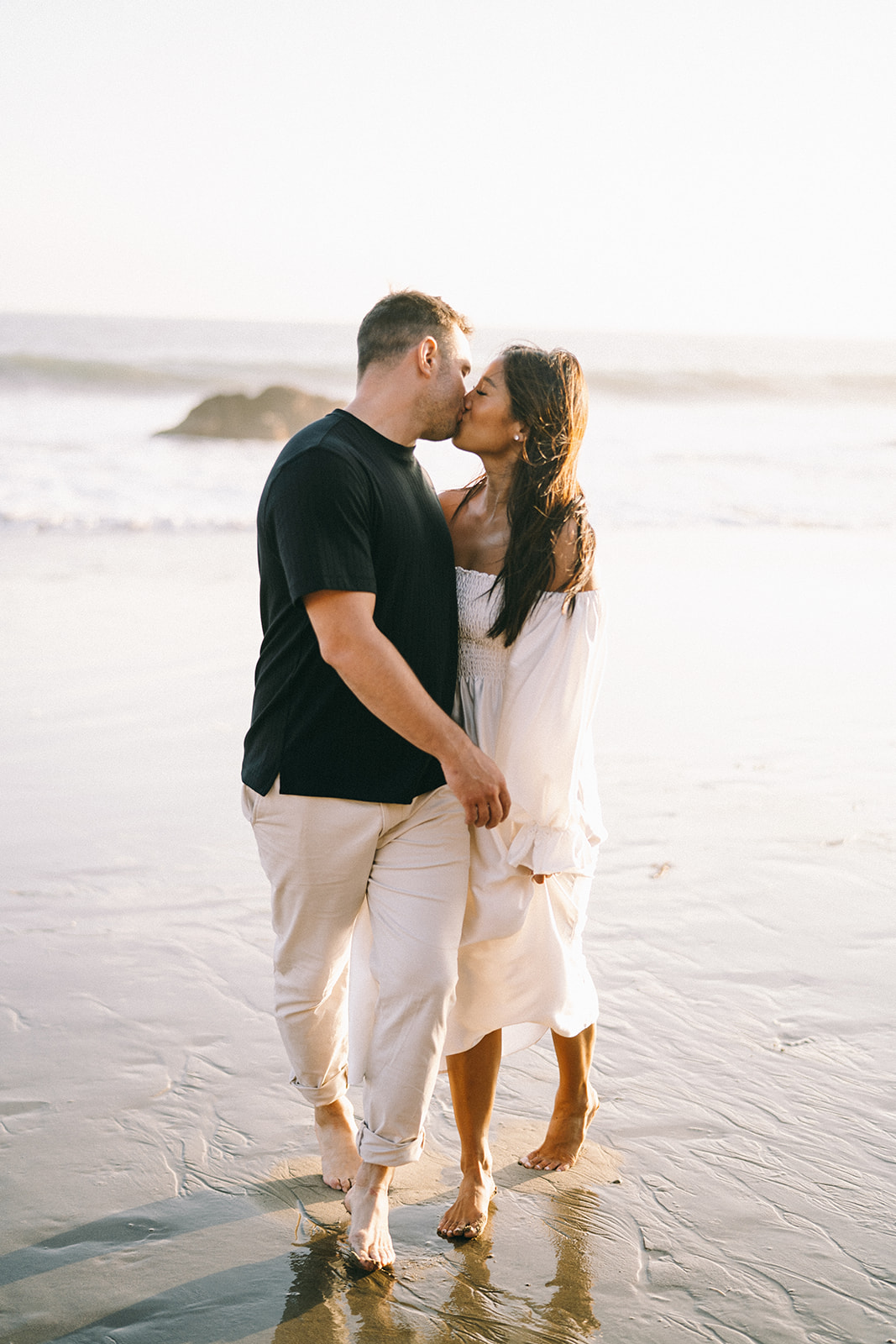 Couple walking along the waterline kissing