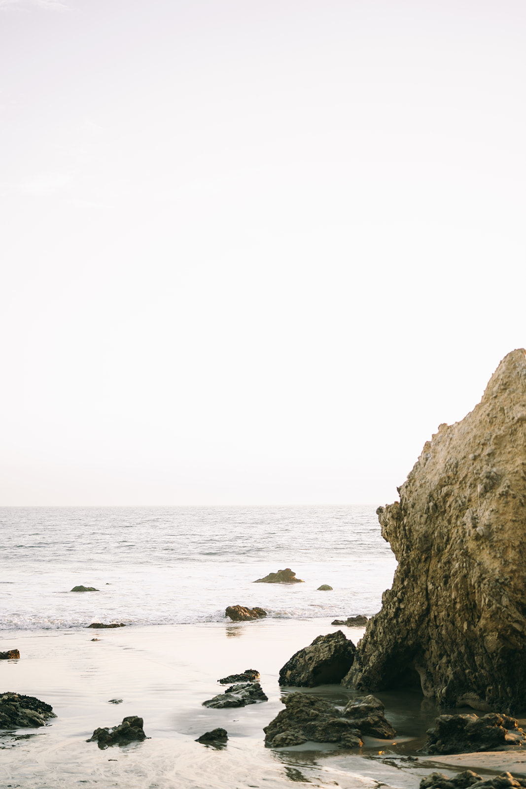 Ocean horizon line in Malibu with small waves and big rocks 