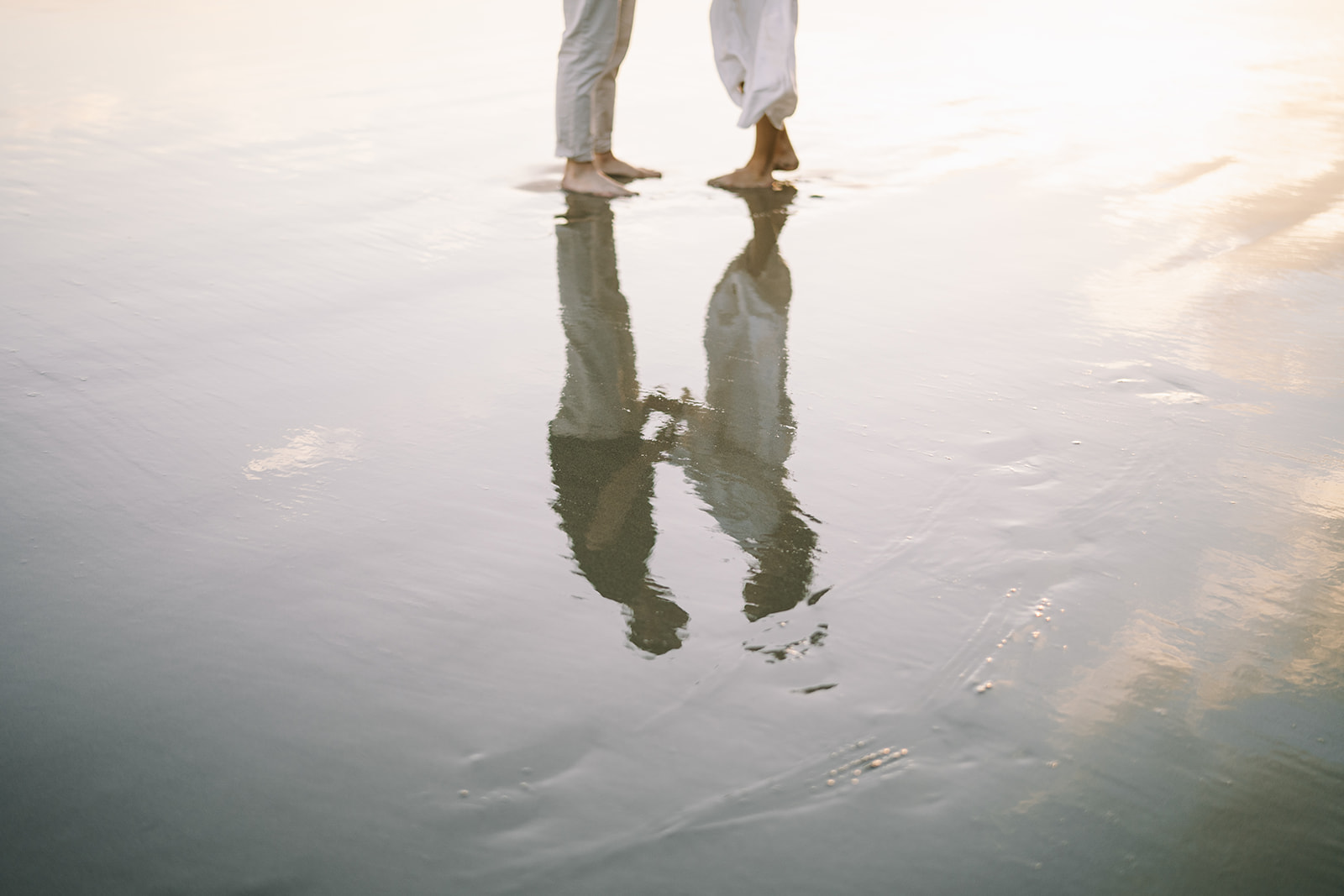 Couple reflected off of glassy water on the beach