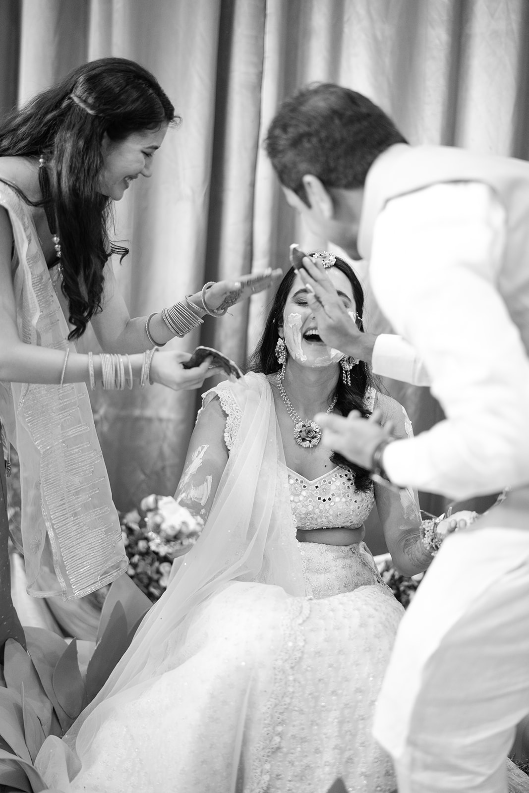 Indian bride laughing with her family in black and white